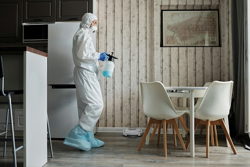 Person in a hazmat suit spraying a kitchen